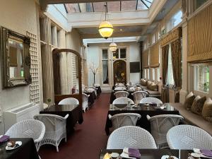 唐克斯特Rossington Hall的餐厅设有桌子、白色椅子和天花板