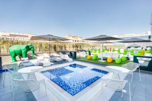 迪拜Studio M Arabian Plaza Hotel & Hotel Apartments的户外庭院设有游泳池和桌椅。