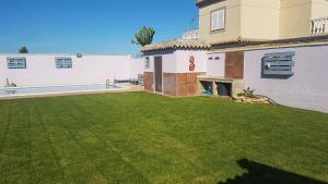 奇皮奥纳Casa Rústica vacacional FILIGRANA en Sanlúcar de Barrameda Zona Montijo的一片绿色草堆的房子的院子