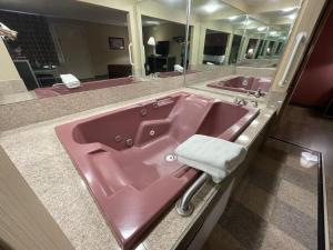 东哈特福德Economy Inn的带大镜子的浴室内的粉红色水槽