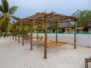 基济姆卡济Bella Vista Resort Zanzibar的海滩上一组椅子,有屋顶