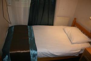 伦敦伯爵府花园酒店的一间卧室配有一张带白色床单的床和一扇窗户。