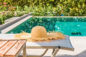 康托卡利My Mediterranean Corfu Luxury Villa with Private Swimming Pool的坐在泳池旁的长凳上的草帽