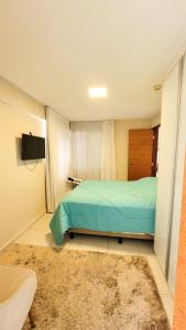 纳塔尔DELUX BEIRA-MAR NATAL Flat的一间卧室配有一张床、一台电视和一张地毯。