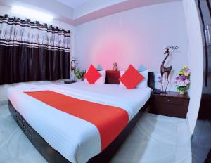 贾姆讷格尔HOTEL HARMONY的一间卧室配有一张带红色和白色床单的大床