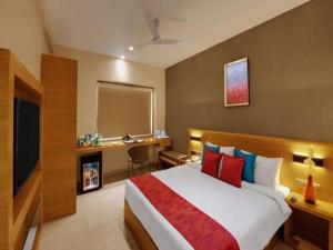 巴罗达Hotel Suba Elite Vadodara的一间卧室配有一张大床、一张书桌和电视。