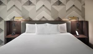 亚特兰大爱默瑞会议中心酒店的一间卧室配有一张带两盏灯的大型白色床。