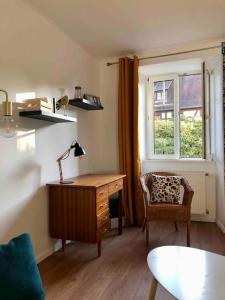 奥贝奈Le Carrousel - Appartement cosy centre Obernai的客房设有书桌、椅子和窗户。