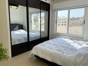 安曼360 Rooftop Apartment in Dabouq的一间卧室设有两张床和大窗户
