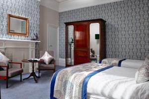 伊斯特布恩The Lansdowne, Eastbourne的一间卧室配有一张床、一把椅子和镜子