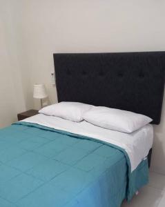 LamasLoft Central en Lamas的一张大床,配有黑色床头板和白色枕头