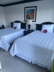 拿骚殖民地俱乐部套房旅馆的卧室内的两张床,配有白色床单