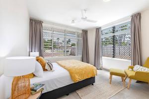 Nightcliff'Botanica Bonita' A Stylish Nightcliff Hideaway的一间卧室配有一张床、一把椅子和窗户。