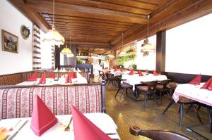 茵特斯托德祖尔珀斯特宾馆的餐厅配有桌椅和红色餐巾
