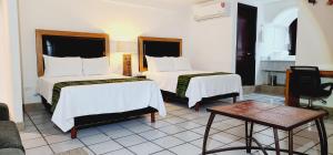 圣何塞德尔卡沃Hotel Boutique Plaza Doradas的酒店客房设有两张床和一张桌子。