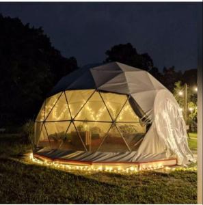 新加坡Seaside Glamping@Heritage Chalet的夜晚在田野里带灯的大帐篷