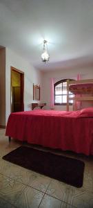 阿蒂巴亚Chácara Sorriso 2的一间卧室配有一张带红色毯子的大床