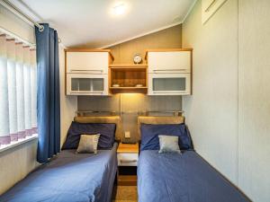 格兰奇奥沃桑茨Links Lodge的小客房内的两张床,配有蓝色的床单
