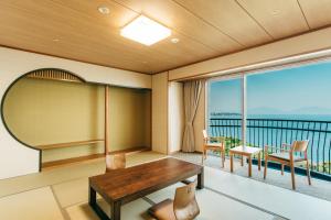 北九州KAMENOI HOTEL Genkainada的客房设有桌椅和阳台。