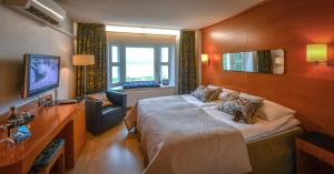 沃卡蒂Hotel Aateli Lakeside的一间卧室配有一张大床和电视