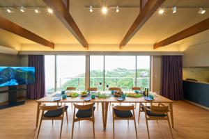 Nakanoスイートヴィラ オーシャンビュー南熱海的一间带桌椅和大窗户的用餐室