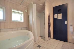 博托比Sommerhus i Marielyst m/Spa og sauna - tæt på by og strand的白色的浴室设有浴缸和窗户。