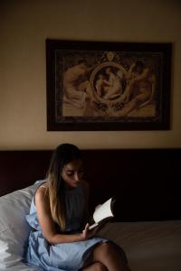 罗卡拉索小百合酒店的坐在床上读书的女人