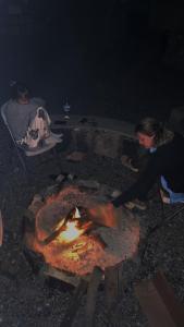 Al HūbJabal Shams Mountain Rest House的夜间坐在火坑周围的女人