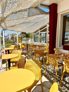 莫吉奥Hôtel Clair de Lune的餐厅设有黄色的桌椅和窗户。