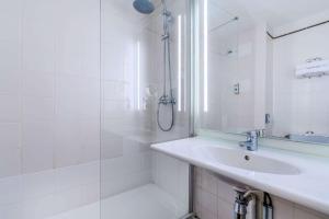 塞纳河畔伊夫里基里亚德巴黎波特伊芙酒店的白色的浴室设有水槽和淋浴。