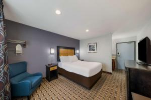 丹顿Quality Inn - Denton的酒店客房,配有一张床和一张蓝色椅子