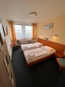 利托梅日采拉贝酒店的一间设有两张床和一张桌子及椅子的房间
