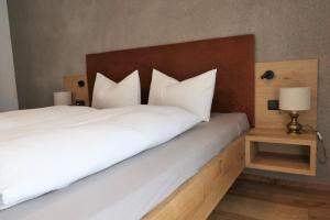 佩尔卡BioTop Appartement Kronplatz的卧室配有白色的床和木制床头板