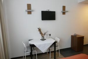 维也纳Comfy Mini Apartments Vienna的一张带椅子的白色桌子和墙上的电视