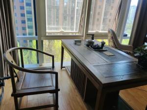 北京Chaoyang Joy City Hardcover Apartment的窗户间配有一张木桌和椅子