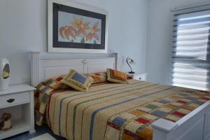 圣胡安海滩Playa San Juan on the Beach的白色卧室配有一张带彩色毯子的床