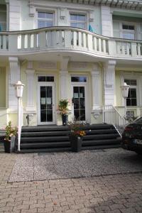 巴特萨尔茨乌夫伦玫瑰园酒店的白色的房子,设有楼梯和阳台