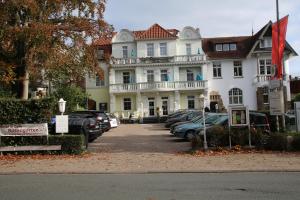 巴特萨尔茨乌夫伦玫瑰园酒店的一座大型白色房子,前面有汽车停放
