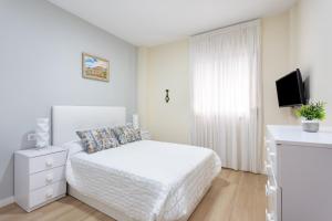 圭马尔港Home2Book Charming Apartment Puertito de Güímar的一间白色卧室,配有床和电视