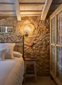 赫罗纳Els Masos de Caula的一间卧室设有石墙、一张床和一张带台灯的桌子