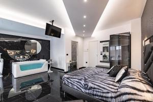 莱切Prezioso suites & rooms的一间带浴缸、一张床和电视的卧室