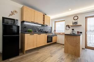 阿拉巴Appartamento Césa Ines的厨房配有黑色冰箱和木制橱柜。