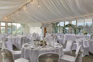 伍德布里奇Ufford Park Resort的一间设有桌椅和白色床单的房间
