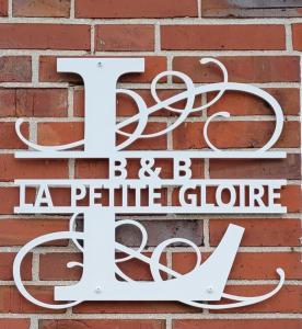 PogumLa Petite Gloire的砖墙上的白色标志,上面写有字母f和蝴蝶音箱