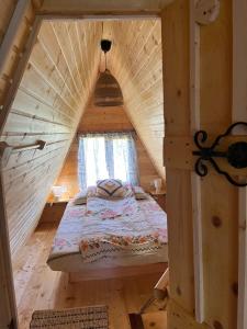 MinciuneştiCrângul Verde的木制房屋内的一张床位,设有窗户