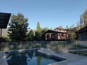 卢汉德库约Casa La Encantada, en el pedemonte mendocino的一个带围栏和房屋的游泳池