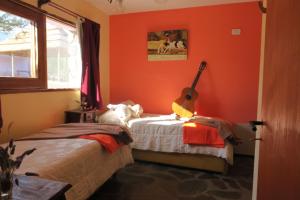 梅洛Cabañas Yanasuy的一间卧室拥有橙色的墙壁,床上配有吉他