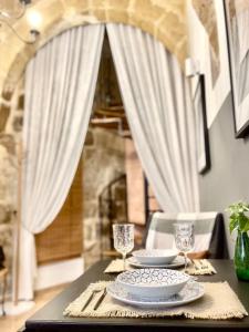 维多利亚300yr old, self catering, tiny house in Victoria Centre, Gozo的一张桌子,上面放着两盘盘酒杯