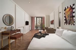 伊斯坦布尔Gatto Suites&Residence的一间卧室配有一张床、一张书桌和一面镜子