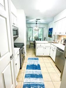基洼岛The Bromeliad at Turtle Cove Villas的厨房配有白色橱柜和蓝色地毯。